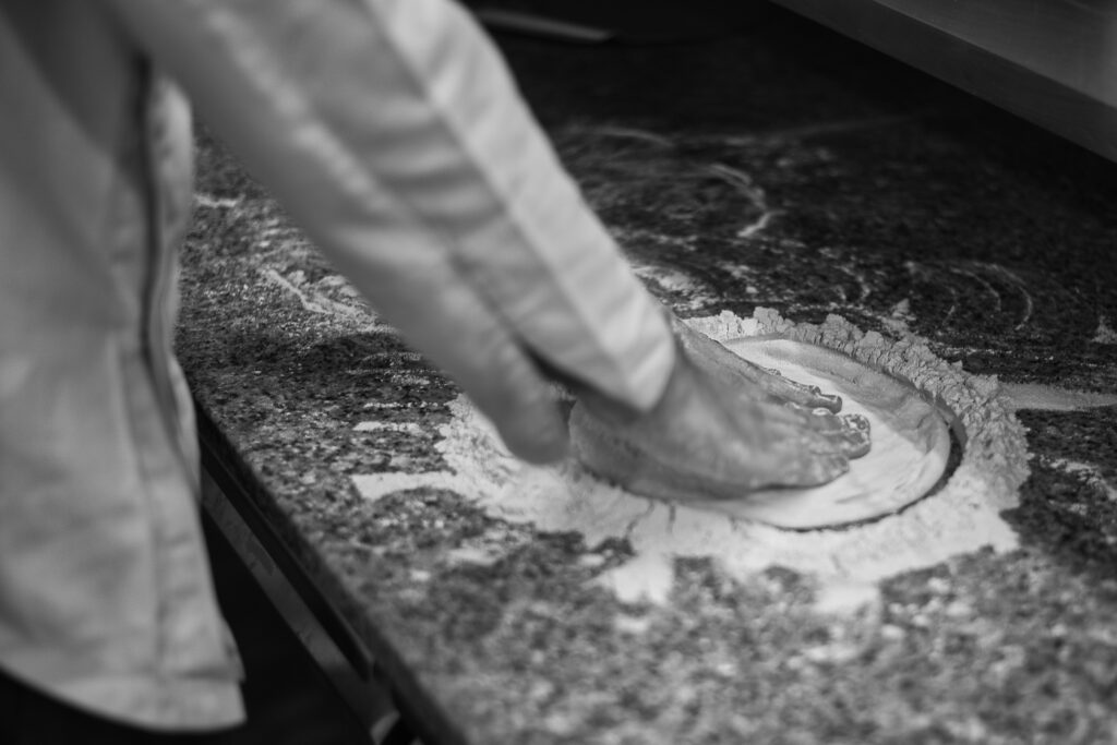 Imatge en blanc i negre  d'unes mans preparant una pizza